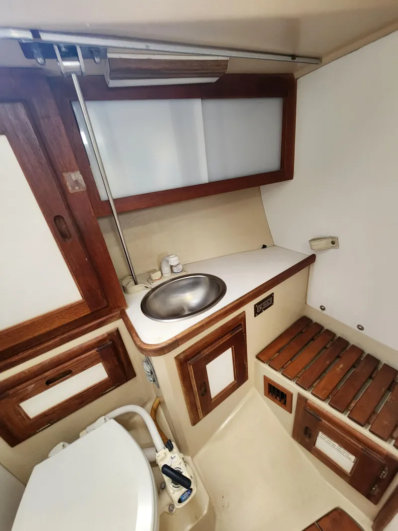 Slide: The Image of 1987 Catalina 36 boat bathroom with sink, wooden cabinets, and toilet. - 33
