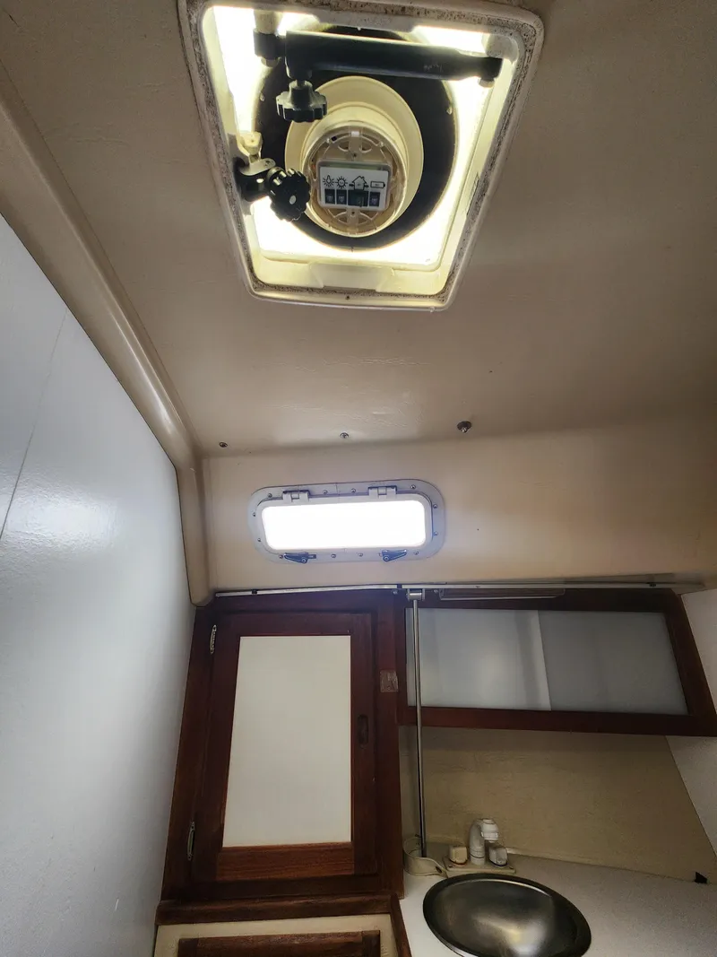 Slide: The Image of Interior of a 1987 Catalina 36 sailboat, featuring a ceiling hatch and compact bathroom area. - 35