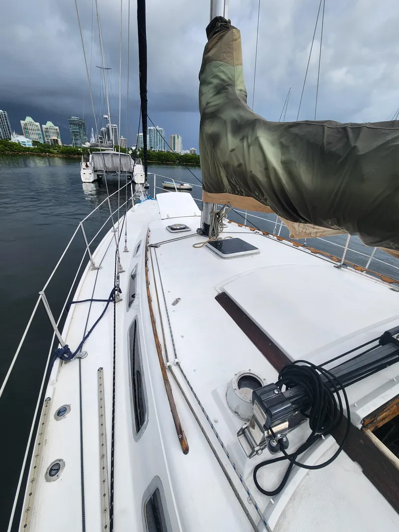 Slide: The Image of 1987 Catalina 36 sailboat docked, with city skyline in the background under cloudy skies. - 4