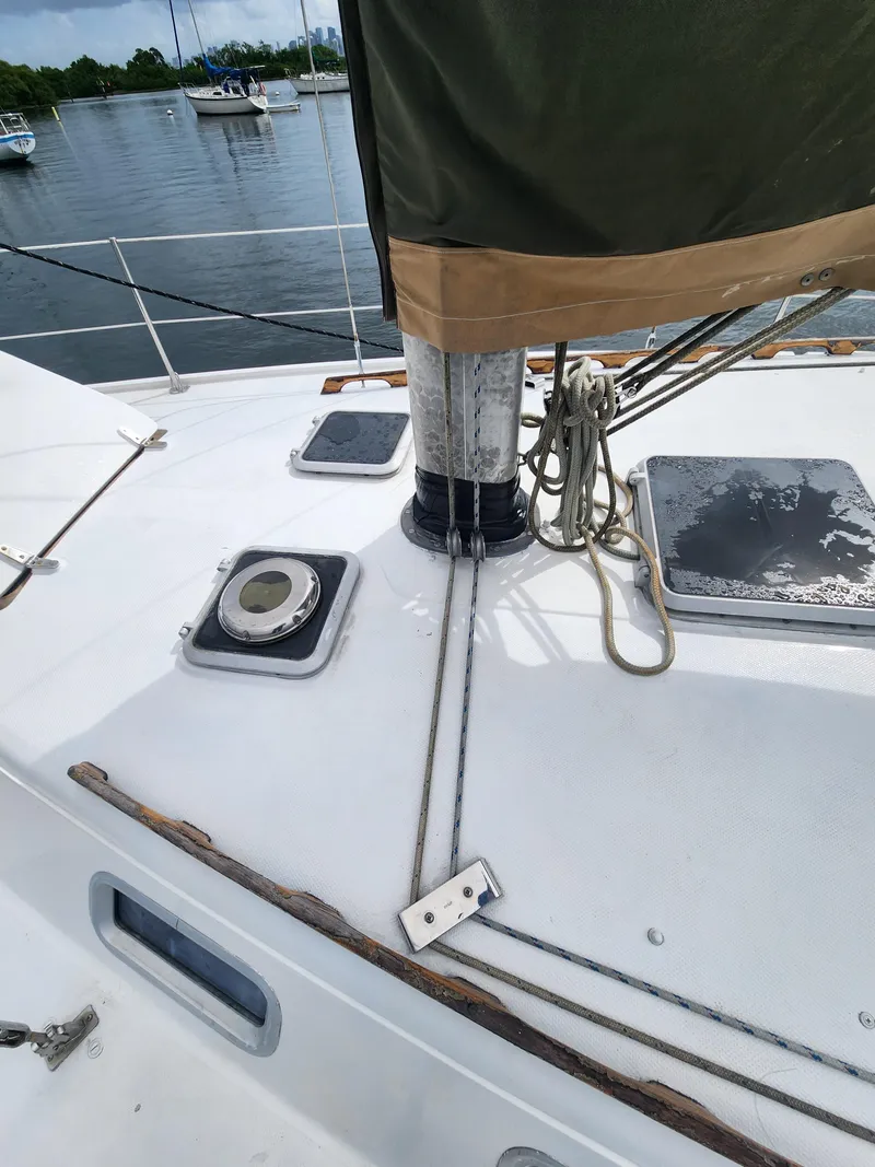 Slide: The Image of 1987 Catalina 36 sailboat deck with rigging and hatches, moored in a calm marina. - 5