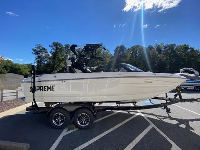 Slide: The Image of 2025 Supreme S220 boat on trailer in sunny parking lot. - 2