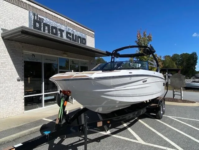 Slide: The Image of 2025 Supreme S220 boat on trailer outside dealership under clear blue sky. - 3