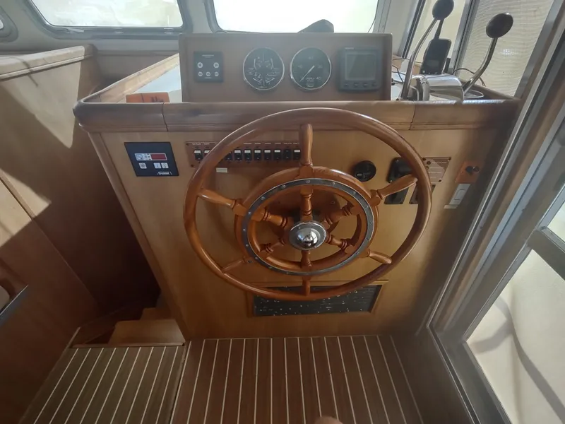 Slide: The Image of 2004 Mainship 400 Trawler helm with wooden steering wheel and navigation instruments. - 13