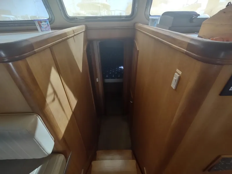 Slide: The Image of Interior stairs of 2004 Mainship 400 Trawler with wooden finish and natural light. - 24