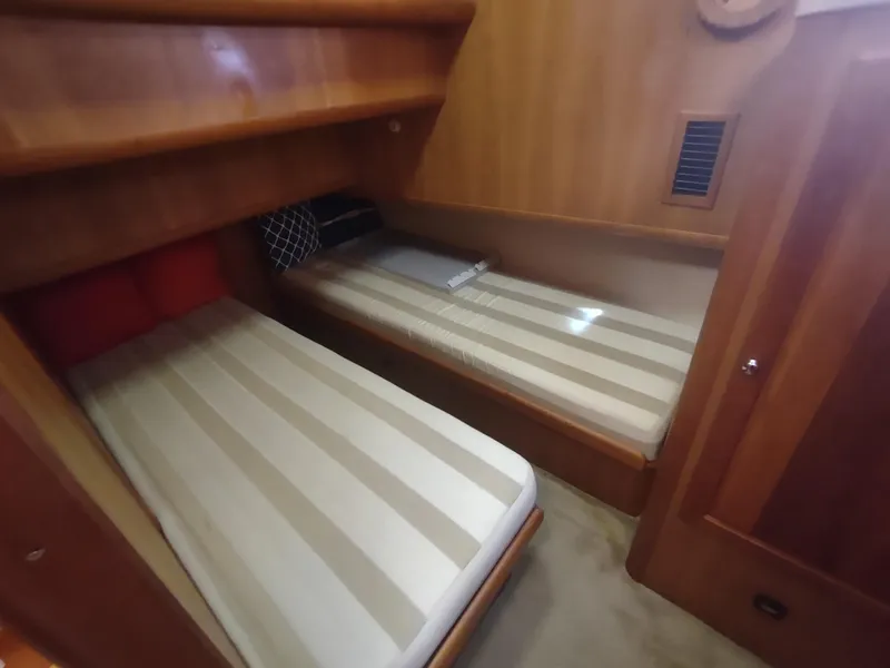 Slide: The Image of 2004 Mainship 400 Trawler cabin with twin beds and wooden interior. - 31