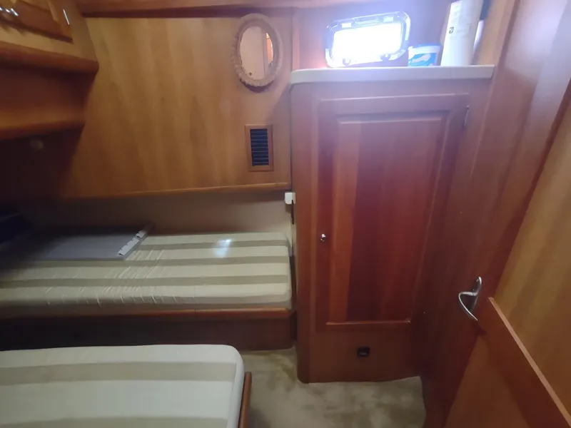 Slide: The Image of Interior cabin of 2004 Mainship 400 Trawler with wooden paneling and twin beds. - 32