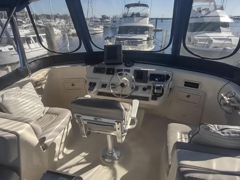 Slide: The Image of 2004 Mainship 400 Trawler helm with marina view, featuring modern navigation equipment and comfortable seating. - 43