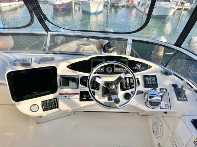 Slide: The Image of 2009 Meridian 391 Sedan helm with steering wheel, navigation controls, and marina view. - 19