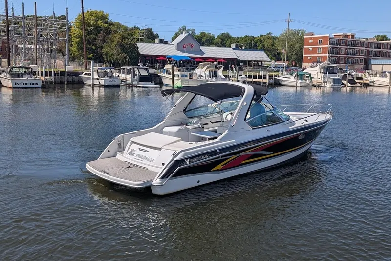 Slide: The Image of 2006 Formula 330 Sun Sport boat cruising in a marina with docked boats. - 2