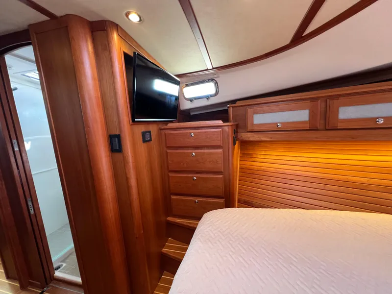 Slide: The Image of 2018 Sabre 45 Salon Express cabin with wood paneling, TV, and storage drawers. - 17
