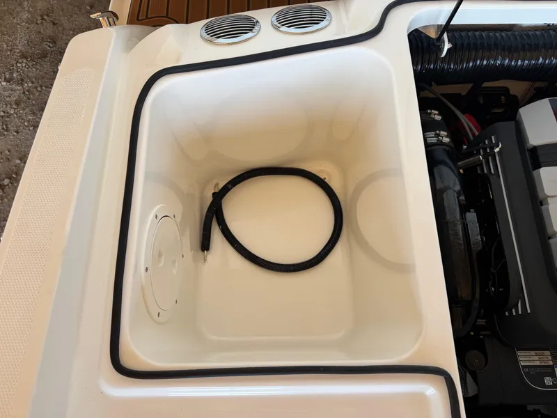 Slide: The Image of 2025 Bayliner VR4 Bowrider I/O engine compartment with storage area and coiled hose. - 15