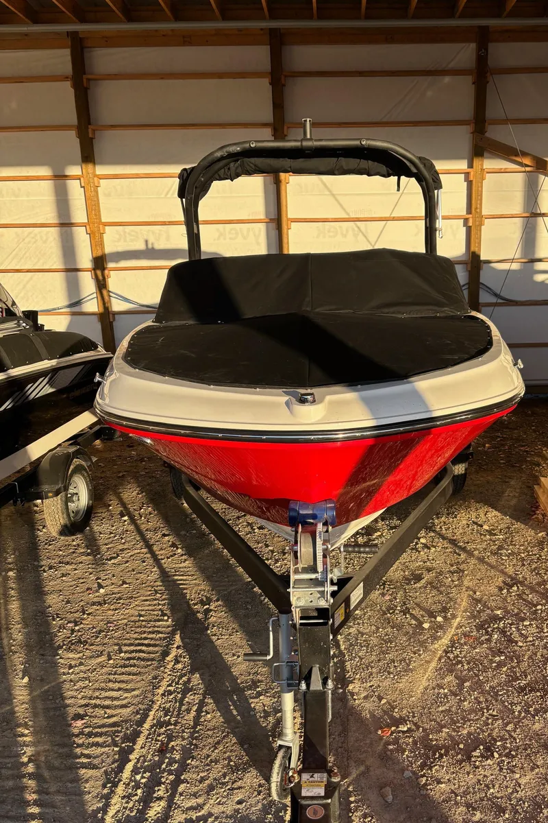 Slide: The Image of 2025 Bayliner VR4 Bowrider I/O boat in storage, red hull, covered, on trailer. - 24