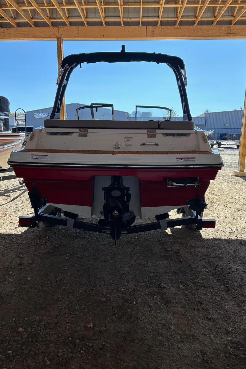Slide: The Image of 2025 Bayliner VR4 Bowrider I/O boat under a wooden shelter. - 4