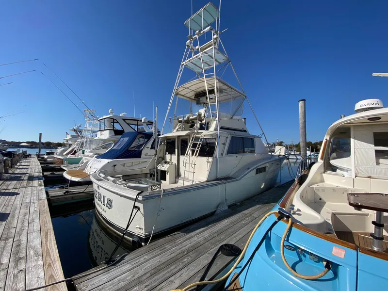 Slide: The Image of 1968 Hatteras 45 Convertible yacht docked at marina under clear blue sky. - 1