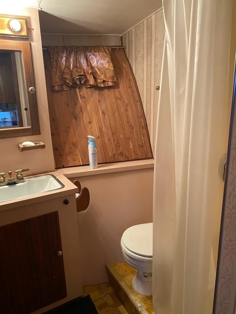 Slide: The Image of Vintage 1968 Hatteras 45 Convertible bathroom with sink, toilet, and shower curtain. - 13