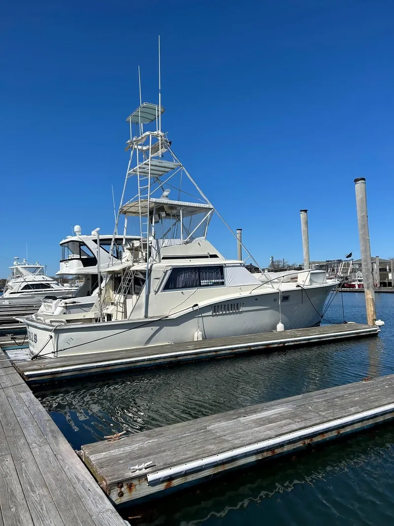 Slide: The Image of 1968 Hatteras 45 Convertible yacht docked at marina under clear blue sky. - 3