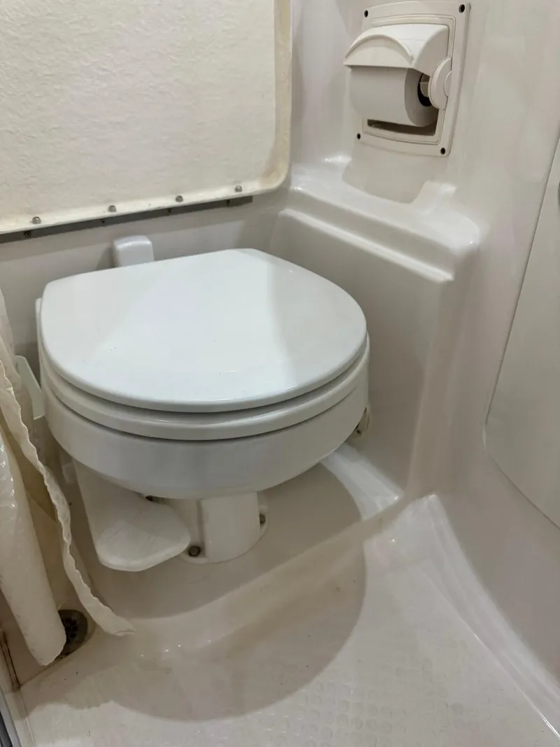 Slide: The Image of 2005 Chaparral Signature 310 boat bathroom with compact toilet and white interior. - 28