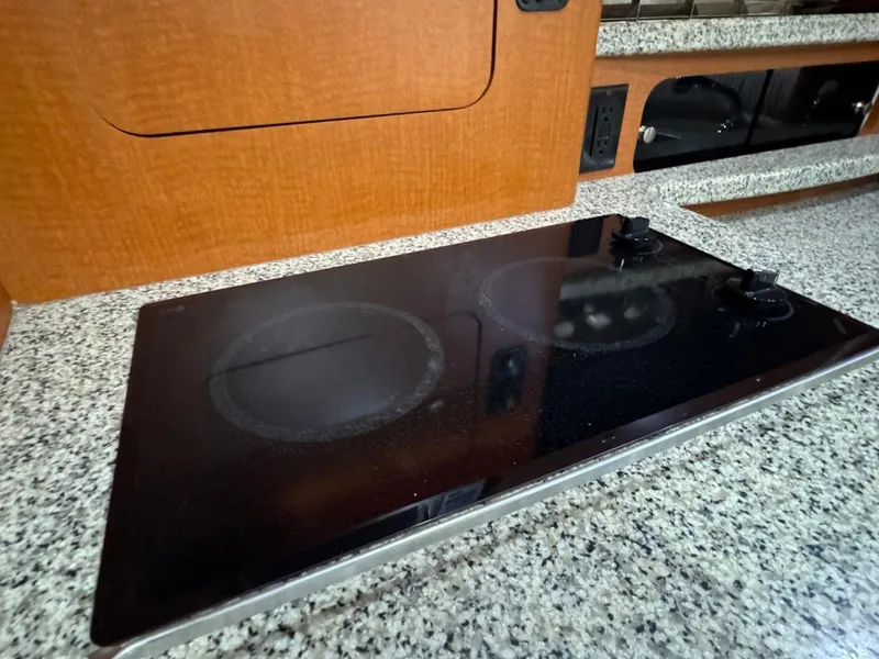 Slide: The Image of 2005 Chaparral Signature 310 kitchen with sleek black cooktop and granite-style countertop. - 34