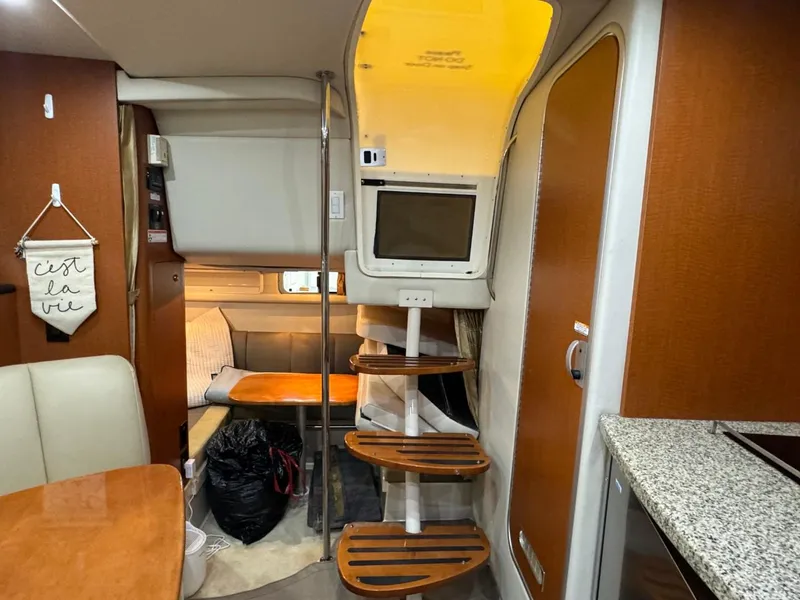 Slide: The Image of 2005 Chaparral Signature 310 interior with wooden steps, seating, and compact kitchen area. - 42