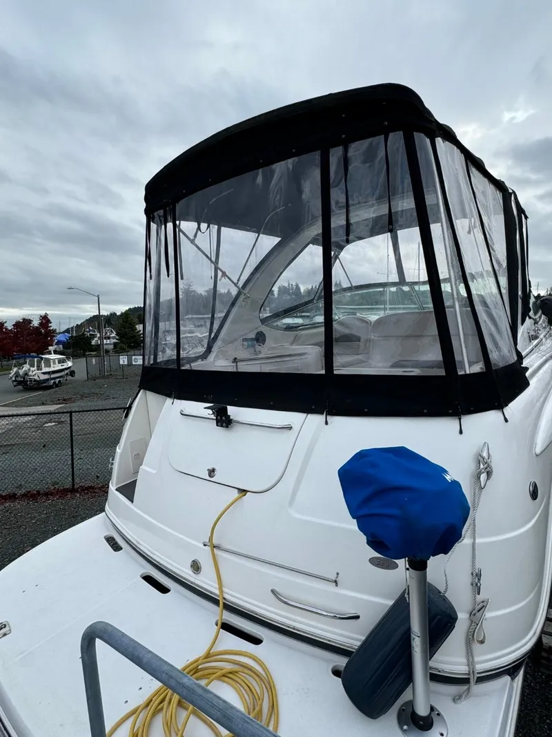 Slide: The Image of 2005 Chaparral Signature 310 boat with black canopy, docked under cloudy skies. - 8