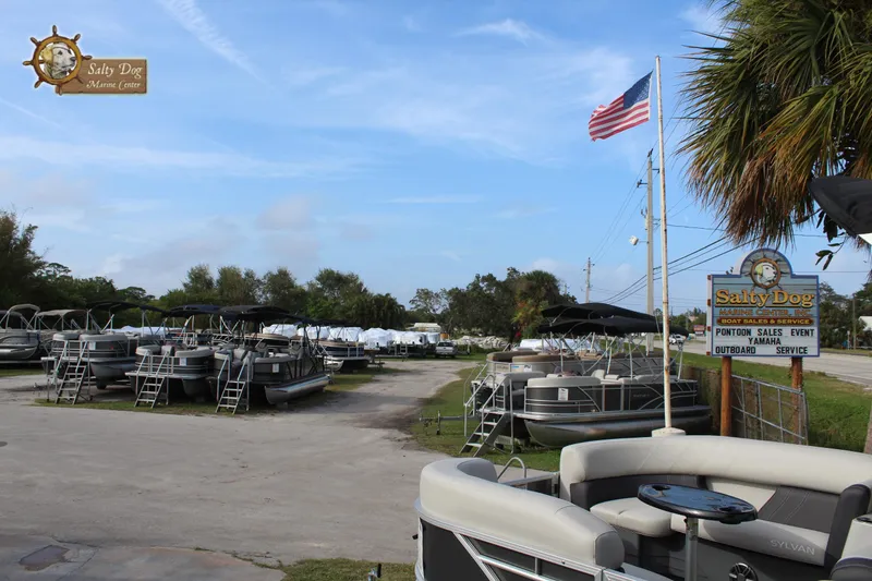 Slide: The Image of Boat dealership with 2025 Sylvan Mirage 822 LZ models, American flag, and Salty Dog sign. - 19