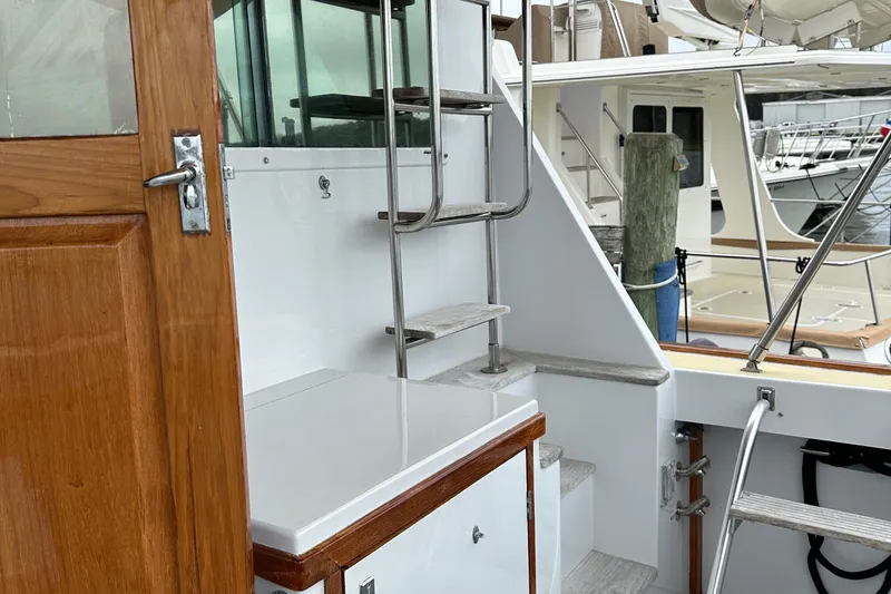 Slide: The Image of 1986 Wilbur Hunt Yachts boat with wooden door, metal ladder, and docked in a marina. - 9