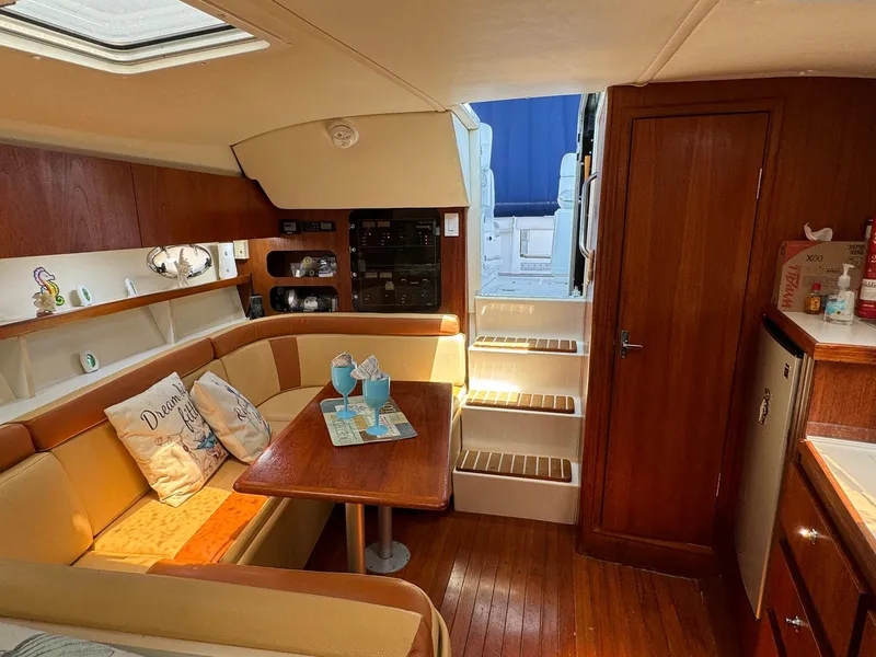Slide: The Image of Interior of 2000 Tiara Yachts 3100 Open, featuring cozy seating and wooden finishes. - 12