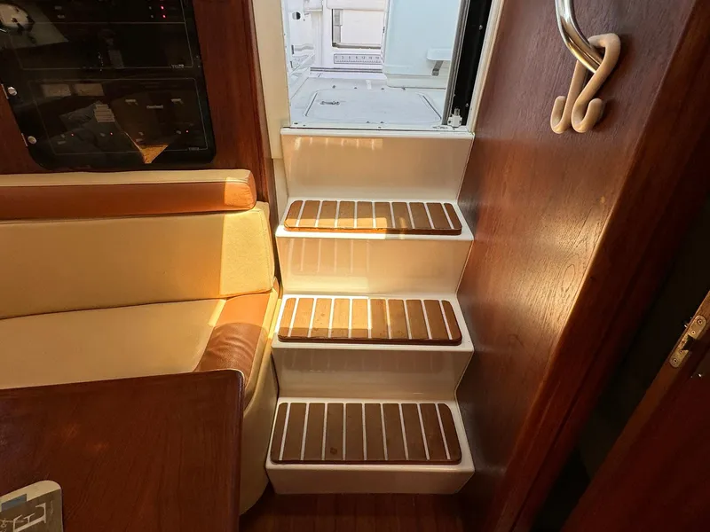 Slide: The Image of Interior stairs of 2000 Tiara Yachts 3100 Open, featuring wooden steps and cozy seating. - 5
