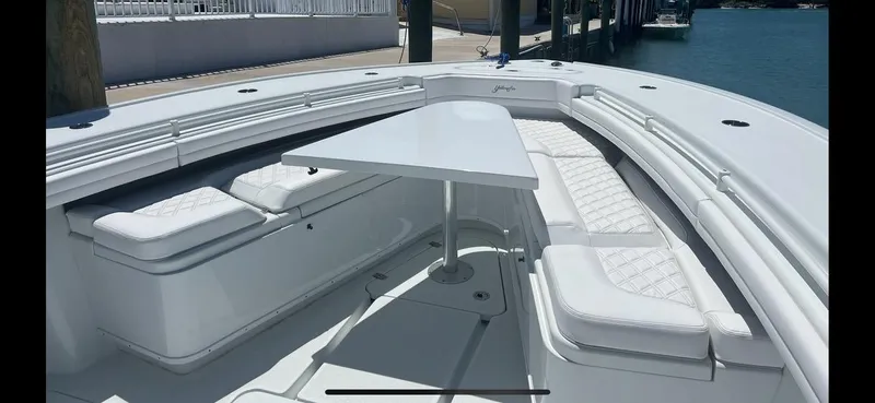 Slide: The Image of 2023 Yellowfin 39 Offshore boat with white seating and table, docked by the water. - 13
