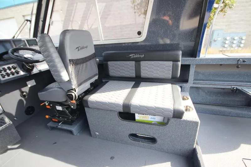 Slide: The Image of 2025 Weldcraft 240 Ocean King interior with gray seating and control panel. - 24