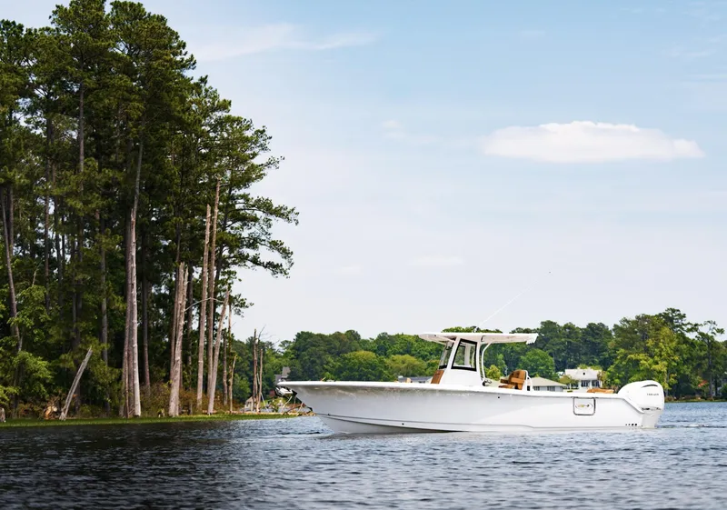 Slide: The Image of 2025 Sea Hunt Ultra 305 SE boat on a serene lake near tall trees. - 10