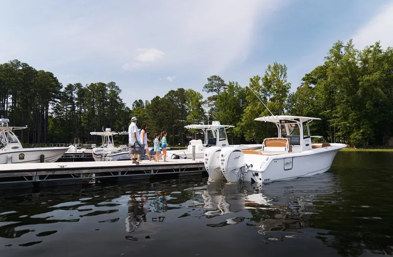 Slide: The Image of 2025 Sea Hunt Ultra 305 SE docked on a serene lake with people nearby. - 17