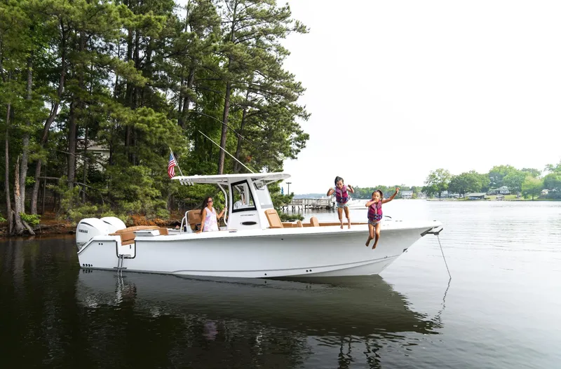 Slide: The Image of 2025 Sea Hunt Ultra 305 SE boat on a serene lake with people enjoying the water. - 2