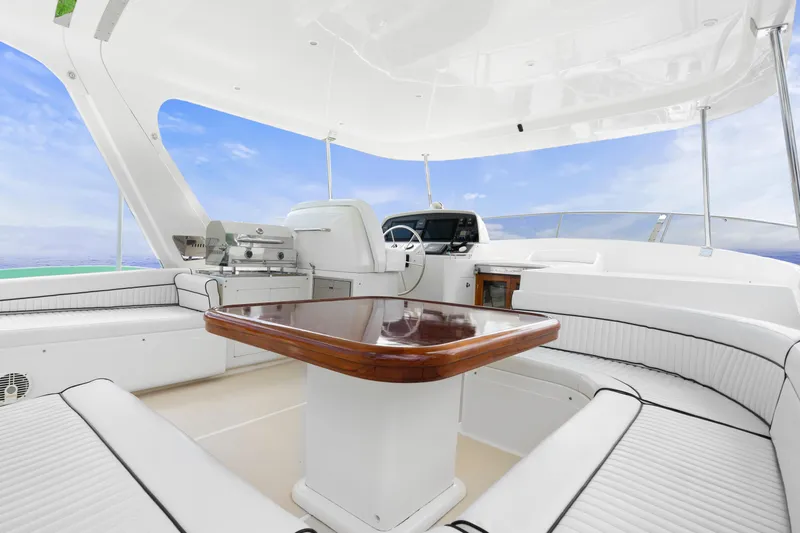 Slide: The Image of Luxurious 2007 Fleming 65 yacht interior with white seating and wooden table against a blue sky backdrop. - 2