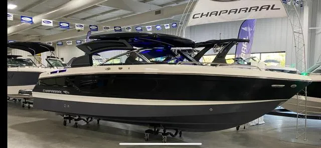 Slide: The Image of 2025 Chaparral 267 SSX boat displayed in showroom, sleek black and white design. - 2