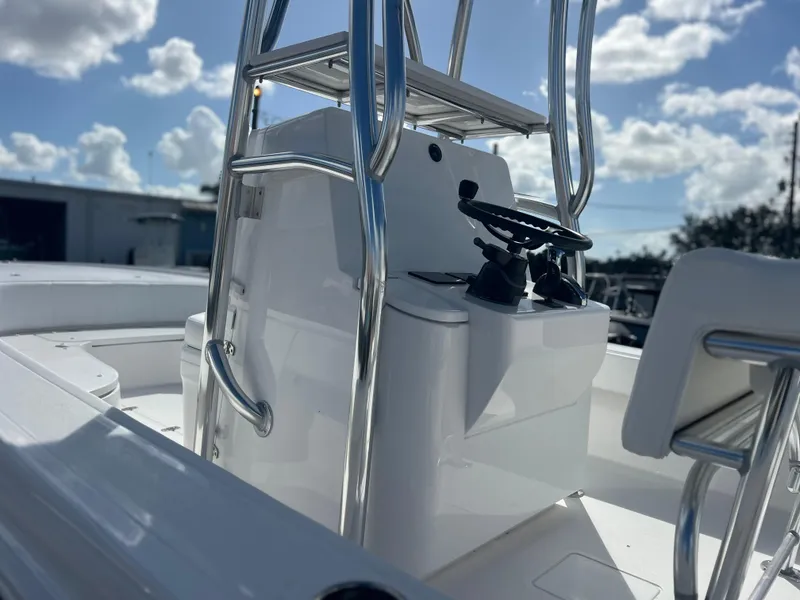 Slide: The Image of 2025 Contender 26 Bay boat console with steering wheel and controls under a sunny sky. - 7