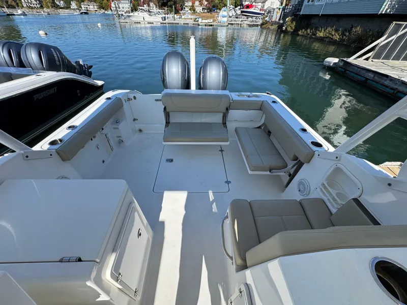 Slide: The Image of 2020 Pursuit DC 266 Dual Console boat interior with seating, docked by the water. - 10