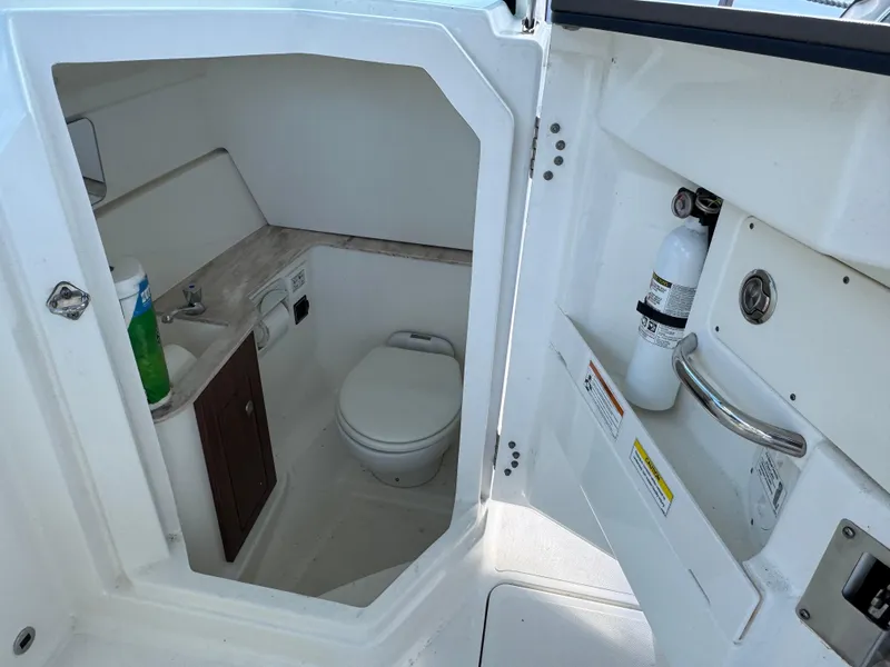 Slide: The Image of 2020 Pursuit DC 266 Dual Console boat bathroom interior with toilet and sink. - 3