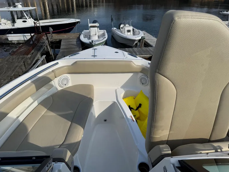 Slide: The Image of 2020 Pursuit DC 266 Dual Console boat interior with seating and docked boats in background. - 40