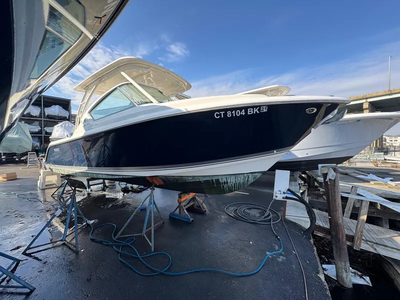 Slide: The Image of 2020 Pursuit DC 266 Dual Console boat on stands, marina background. - 49