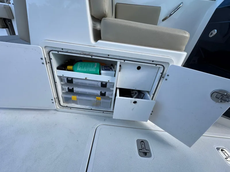 Slide: The Image of 2020 Pursuit DC 266 Dual Console storage compartment with open doors, showcasing organized supplies. - 7