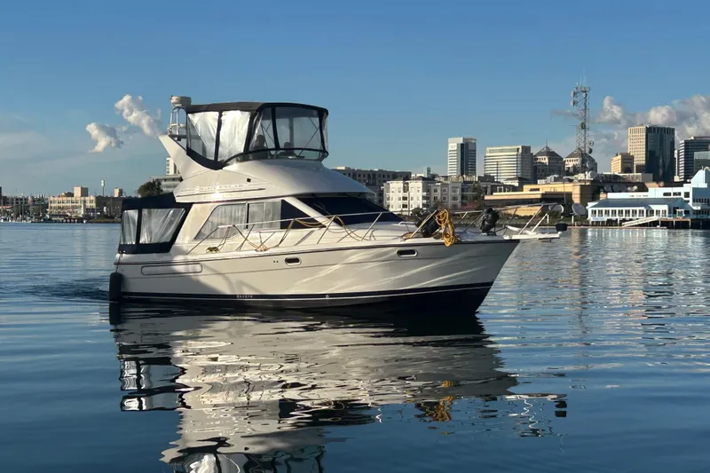 Slide: The Image of 1999 Bayliner 3388 Motoryacht on calm water with city skyline. - 2