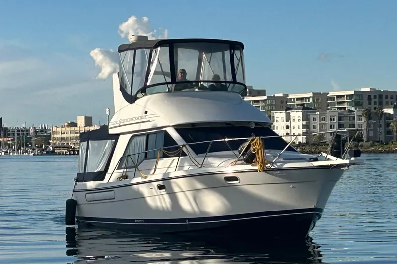 Slide: The Image of 1999 Bayliner 3388 Command Bridge Motoryacht on calm water near urban skyline. - 3