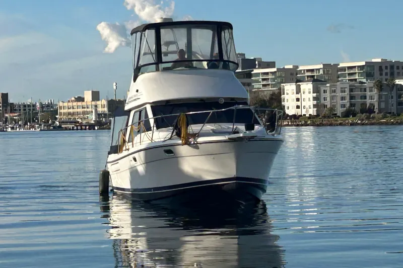 Slide: The Image of 1999 Bayliner 3388 Command Bridge Motoryacht on calm water near urban skyline. - 4