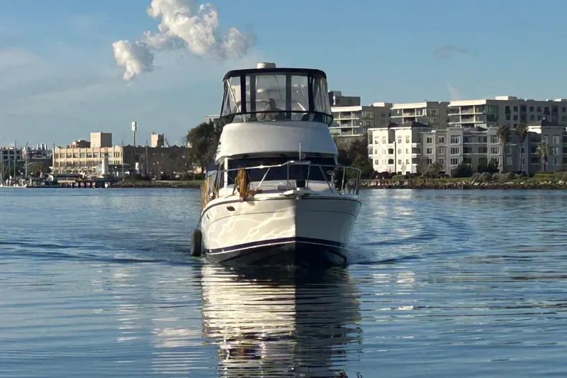 Slide: The Image of 1999 Bayliner 3388 Command Bridge Motoryacht cruising on calm waters near urban skyline. - 5