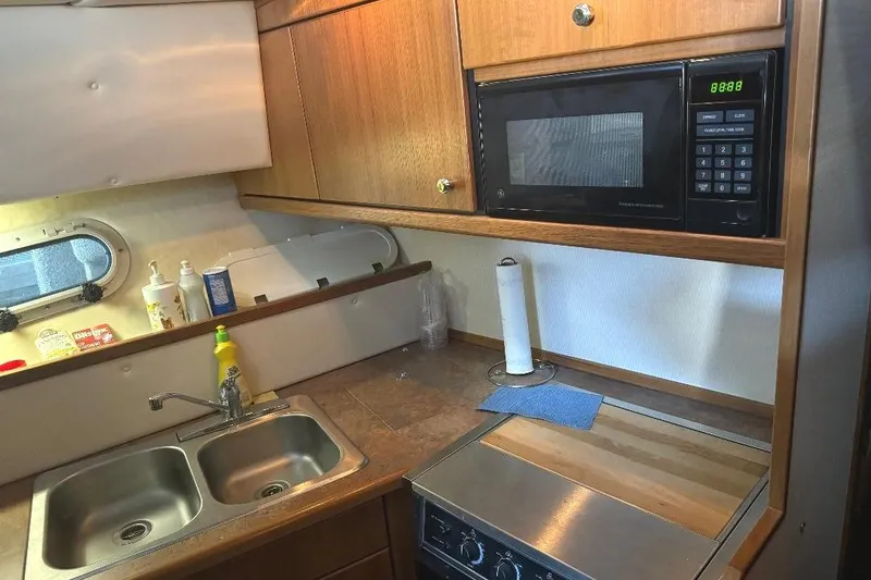 Slide: The Image of 1999 Bayliner 3388 Command Bridge Motoryacht kitchen with sink, microwave, and stove. - 8