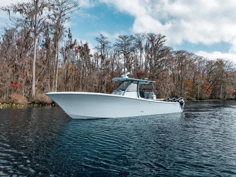 Slide: The Image of 2024 Front Runner 36 Center Console boat on a serene lake with trees. - 2