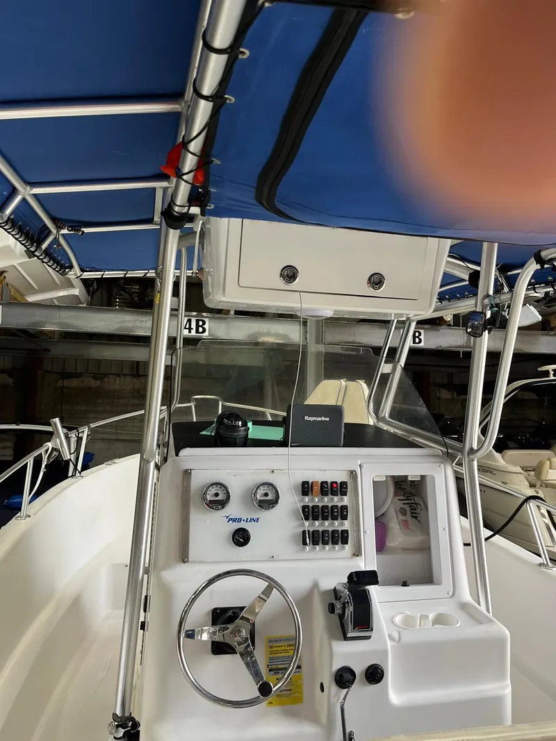 Slide: The Image of 2001 Pro-Line 25 Sport boat interior with steering console and blue canopy. - 12