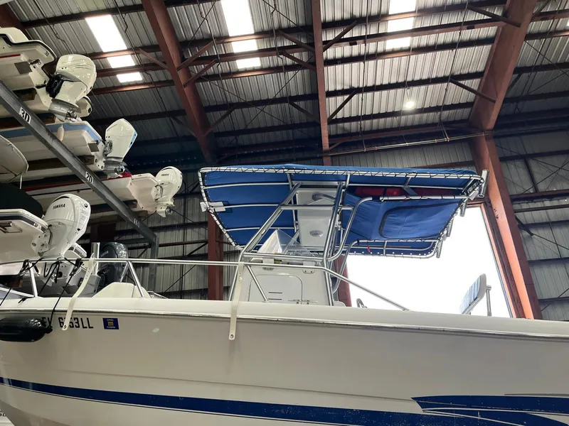 Slide: The Image of 2001 Pro-Line 25 Sport boat in storage, featuring a blue canopy and white hull. - 6