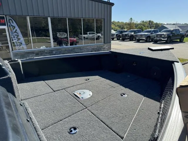 Slide: The Image of 2025 Lund 1875 Impact XS Sport boat interior with carpeted deck, parked outside dealership. - 15